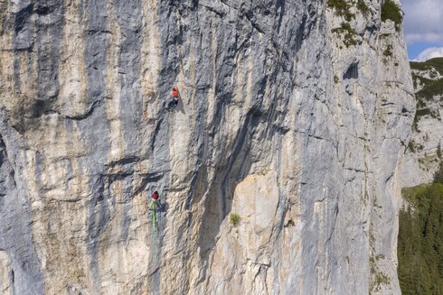 Eine Person klettert auf einer steilen Felswand.