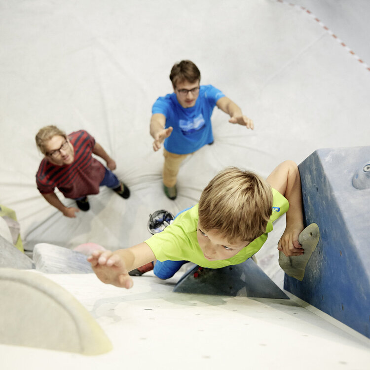 Ein Kind bouldert in der Bergstation in Telfs. Zwei Personen sichern das Kind.