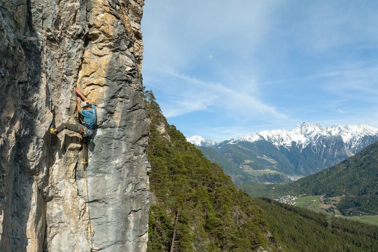 Ein Mann klettert eine Felswand hoch.