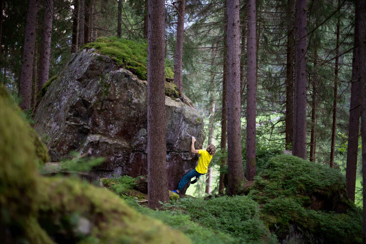 Ein Mann mit einem gelben T-Shirt klettert auf einem kleinen Felsen.