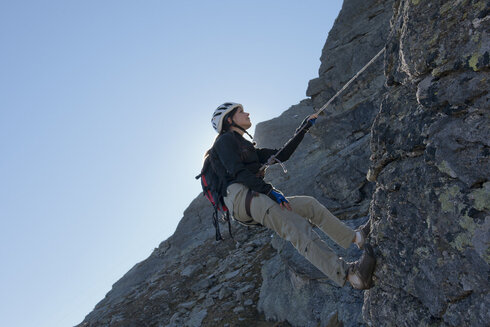 A woman is roped down while sport climbing.