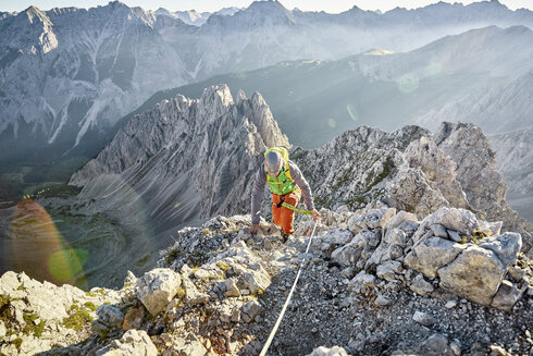 Eine Frau geht am Stahlseil gesichert eine einfache Passage am Innsbrucker Klettersteig.