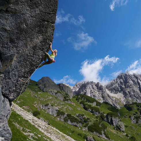 Frau klettert auf einer Felswand.