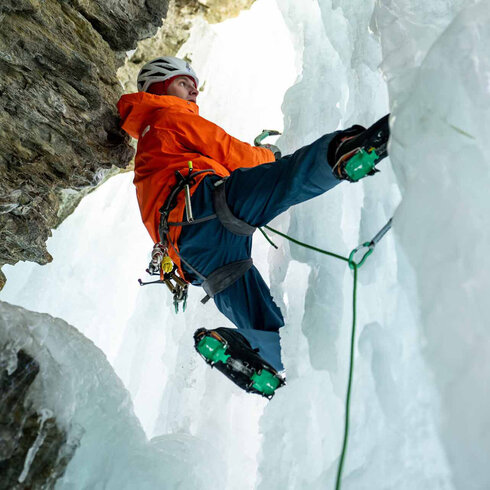 Ein Eiskletterer klettert den Eisfall mit seinen Eisgeräten empor