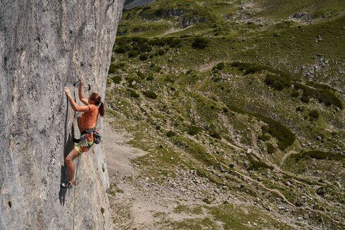 A woman climbs up a slippery rock passage