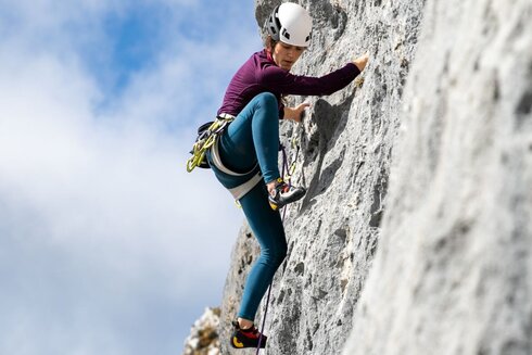 Eine Frau klettert eine Felswand hoch.