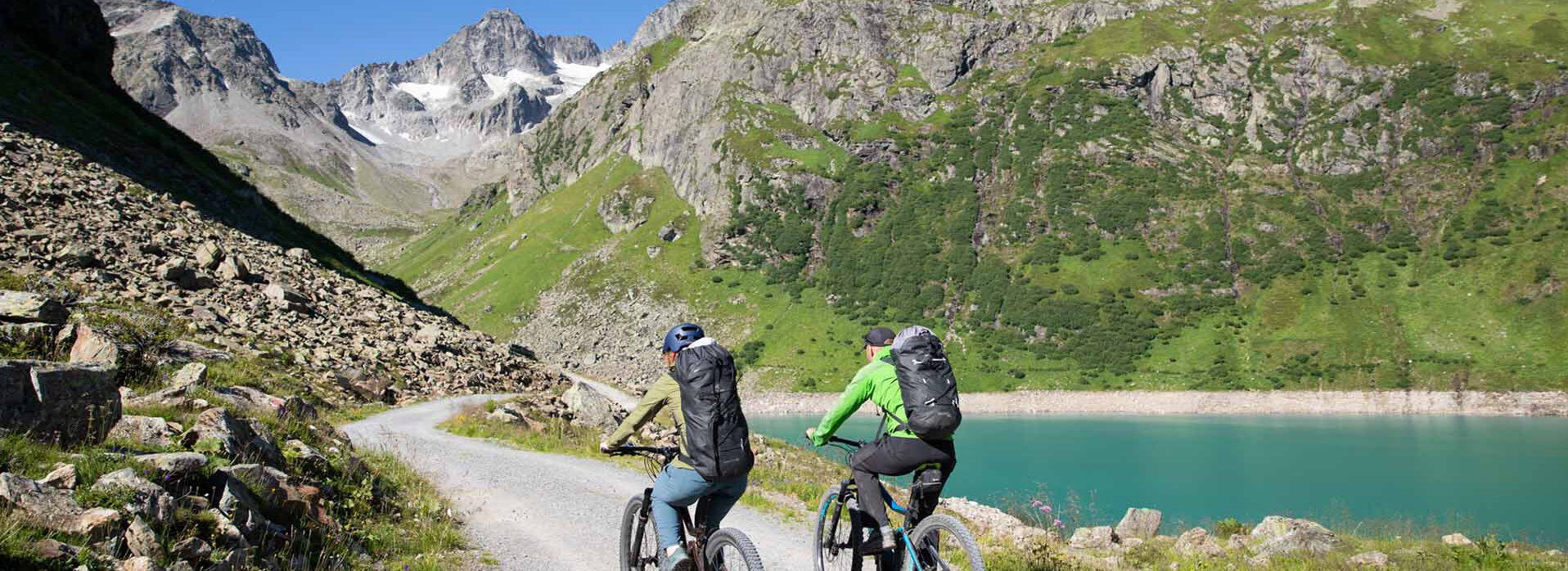 Zwei Fahrradfahrer fahren an einem Teich entlang.