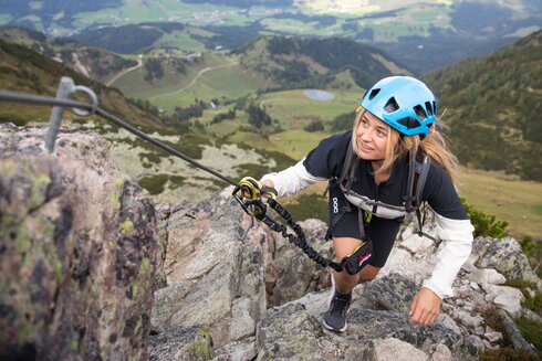 A woman overcomes an easy passage on a via ferrata. 