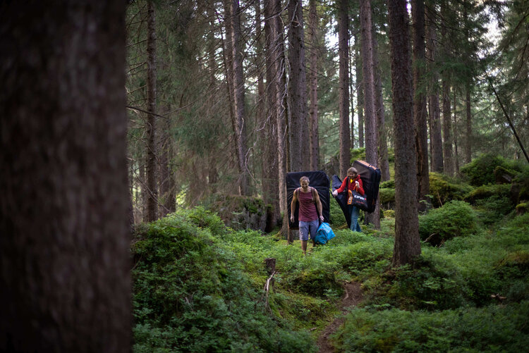 Ein Mann und eine Frauen gehen mit Ausrüstung durch den Wald.